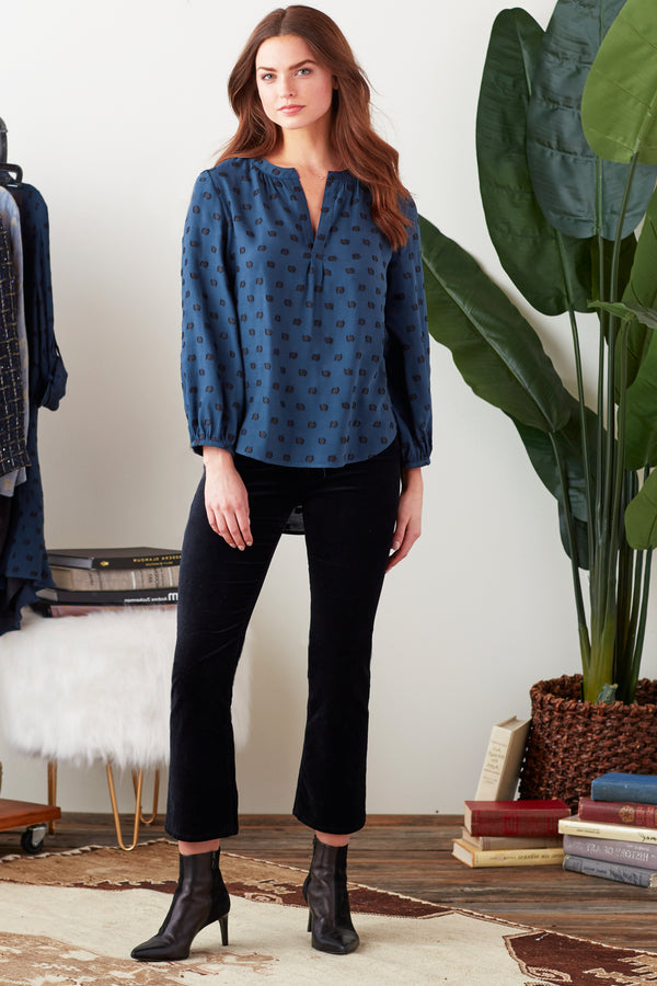 A model wearing the Finley Stephanie top, a popover blouse with a relaxed fit, long sleeves, and a purple paisley pattern.