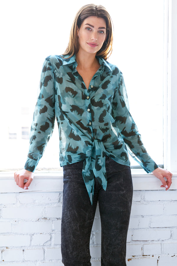 The Finley Lindy shirt, a button up silk-cotton blouse with a semi-fitted shape, a tie front, and teal and black floral print.