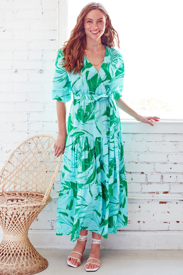 A model wearing the Finley Aerin dress, a long cotton dress with a self belt and a green and white floral palm pattern.