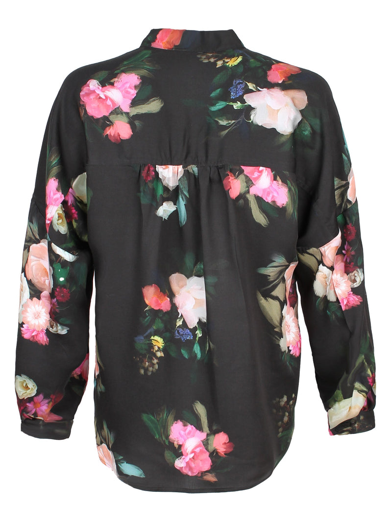 A rear view of the Finley band collar blouse, a button down long sleeve shirt with a drop shoulder and a Dutch floral print.