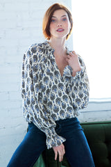 A model wearing the Finley Brette blouson, a ruffled long sleeve blouse with a v-neckline and a vintage medallion print.