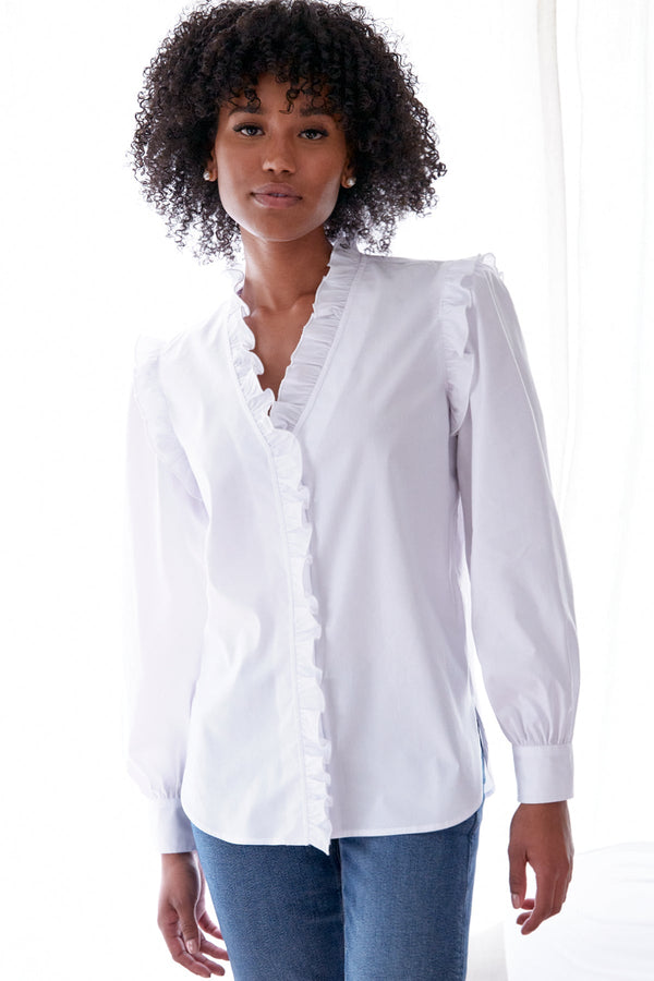 A front view of the Finley Byrdee blouse, a long sleeve white poplin top with ruffled trim, tonal piping, and a v neckline.