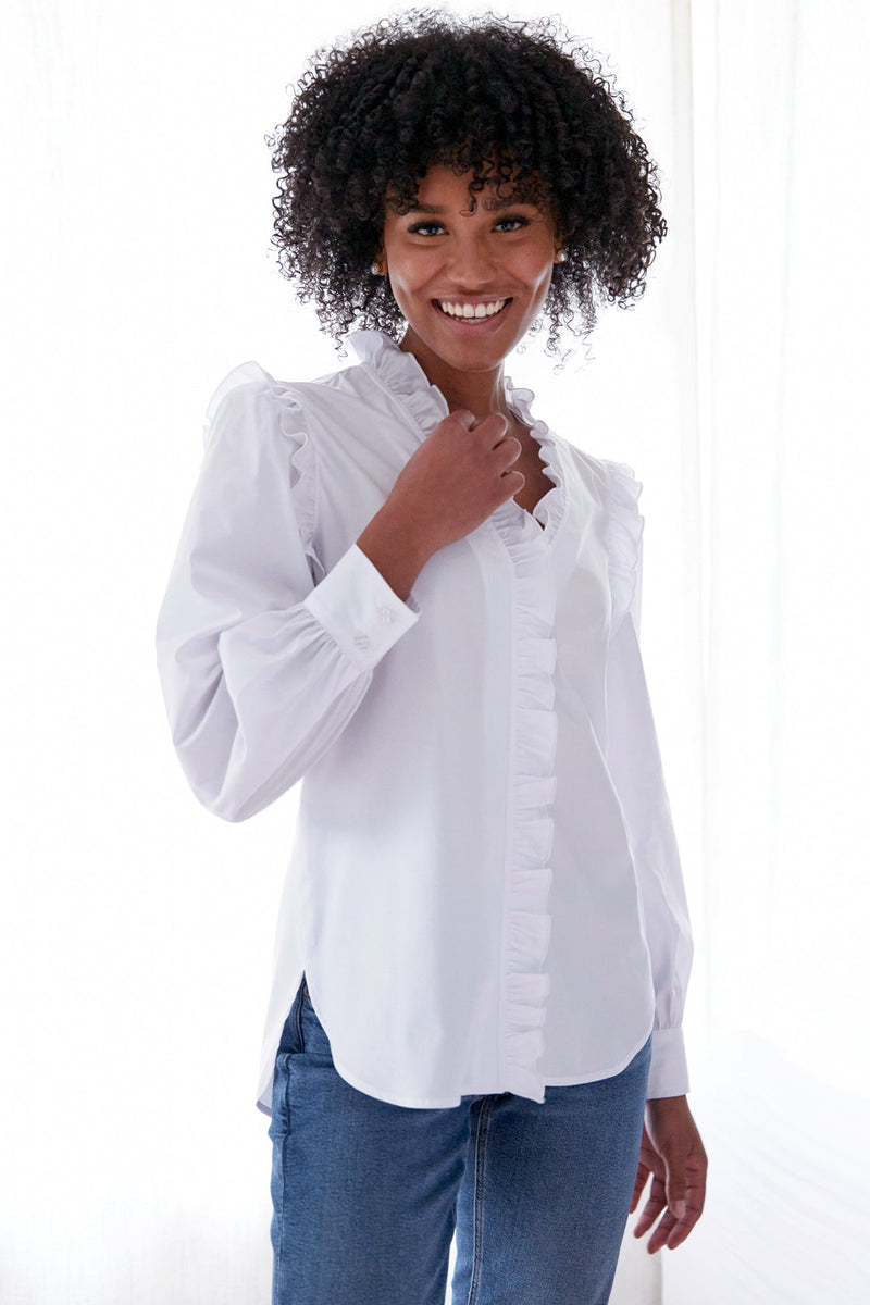 A front view of the Finley Byrdee blouse, a long sleeve white poplin top with ruffled trim, tonal piping, and a v neckline.