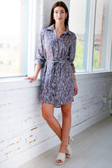 A model wearing the Finley Carter dress, a front tie midi shirt dress with an abstract zig-zag print and a relaxed shape.