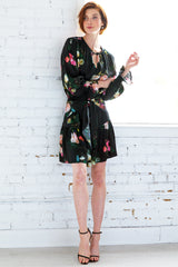 A model wearing the Finley Coco dress, a midi peasant dress with a long sleeves, a front tie and a Dutch floral pattern.