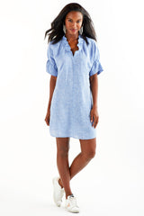 A model wearing the Finley Crosby, a casual washed linen natural gray shirt dress with pockets and ruffled sleeves and collar.
