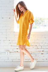 A model wearing the Finley Crosby shirt dress, a washed linen dress with ruffled sleeves and collar and a sage green color.