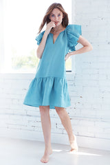 A model wearing the Finley Hattie dress, a pink casual washed linen dress with flounced sleeve and hem and relaxed fit.