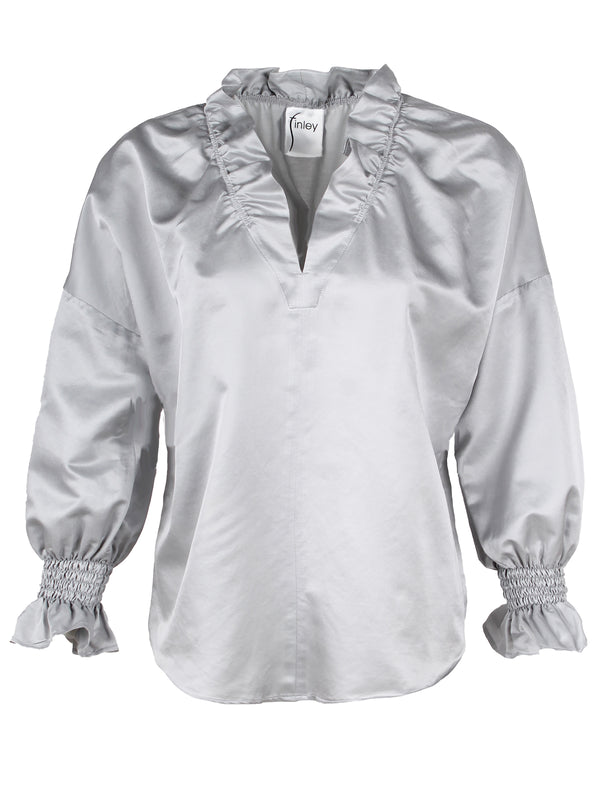 A front view of the Finley Crosby blouse, a long sleeve silver cotton shirt with a v-neck and ruffle detailing.