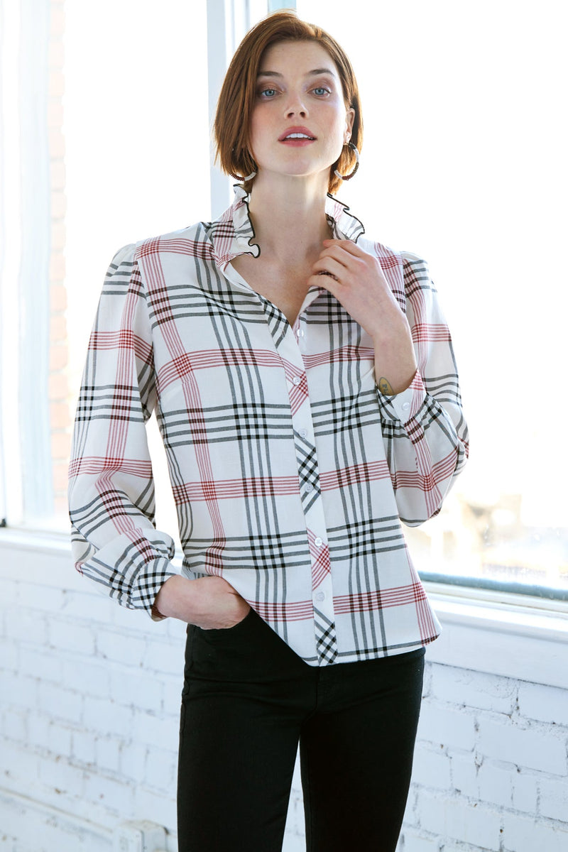 A model wearing the Finley Mystie blouse, a white long sleeve button up silky poplin shirt with a ruffle neckline.