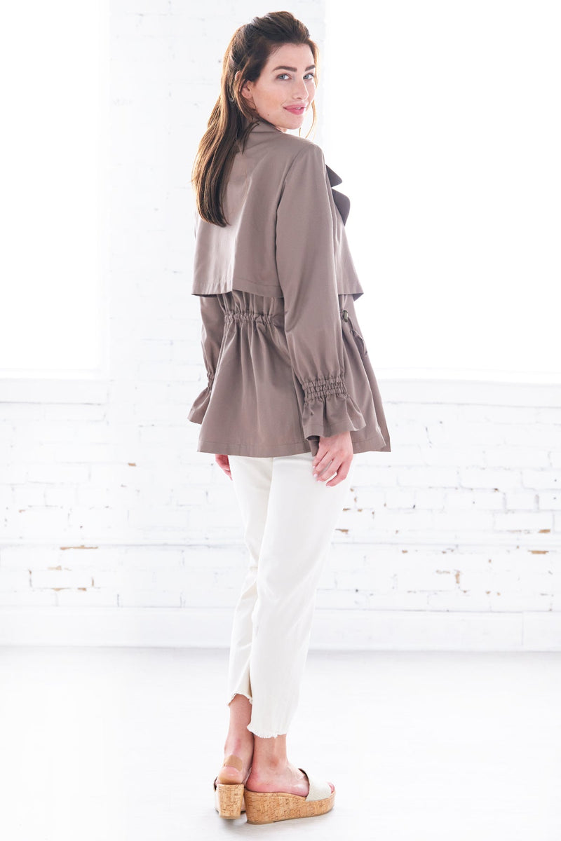 The Finley Sateen jacket, a double breasted drawstring jacket with a front tie, side seam pockets, and a pale brown color.