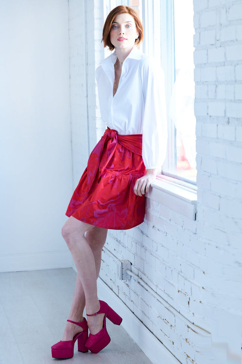 The Finley tiered skirt, a front tie midi skirt with an elastic waistband, flouce ruffle hem, and a red floral Jacquard pattern.