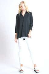A blonde supermodel wearing the Finley trapeze top, a black button-down tunic blouse with an A-line shape and relaxed fit.