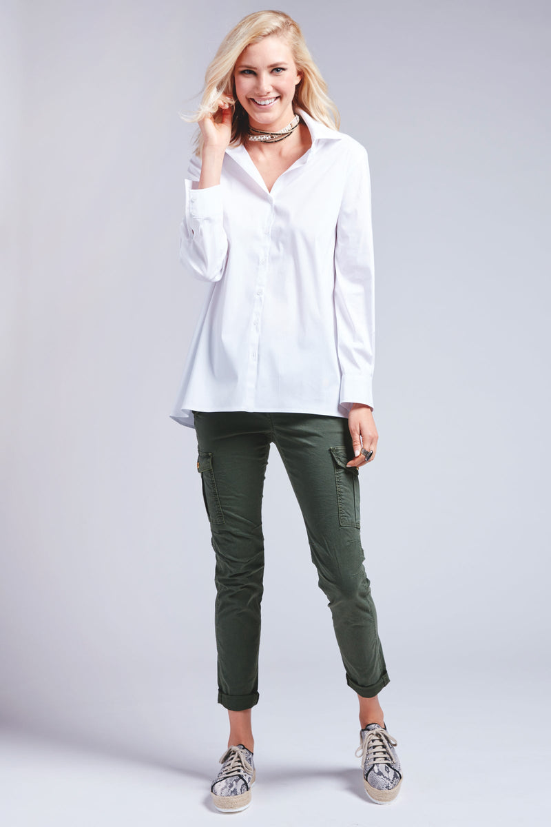 A blonde fashion model wearing the Finley trapeze top, a white full sleeve button-down blouse with an A-line shape and barrel cuff.
